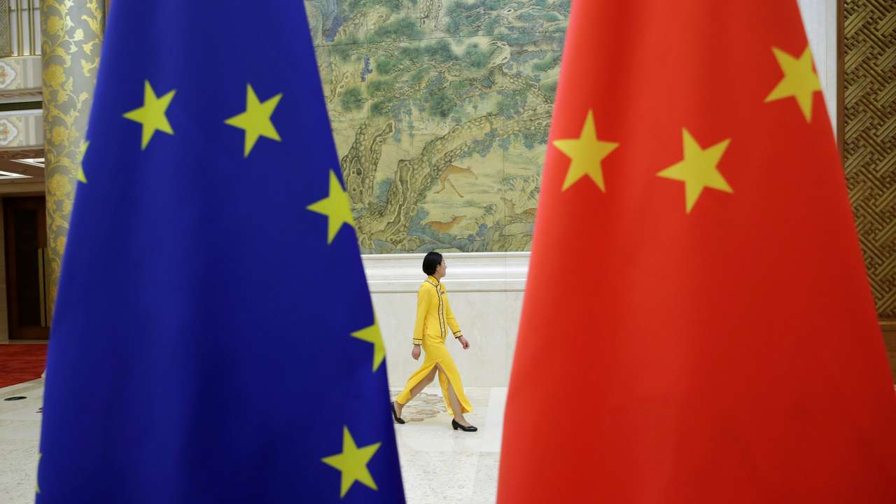An attendant walks past EU and China flags ahead of the EU-China High-level Economic Dialogue in Beijing