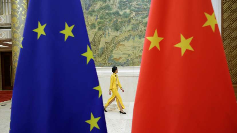 An attendant walks past EU and China flags ahead of the EU-China High-level Economic Dialogue in Beijing