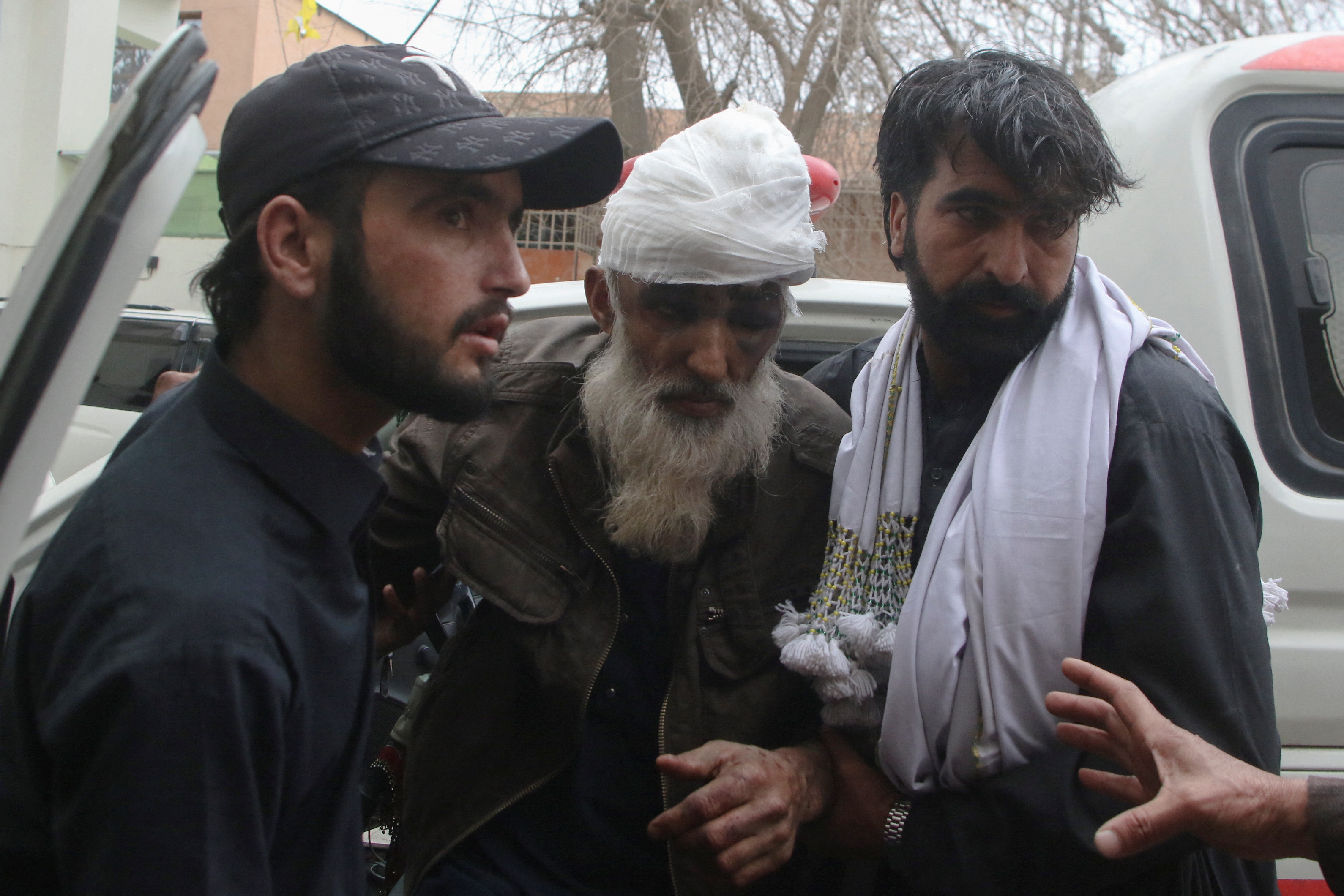 People escort a person who was wounded in a bomb blast on a vehicle carrying coal miners, at a hospital in Quetta