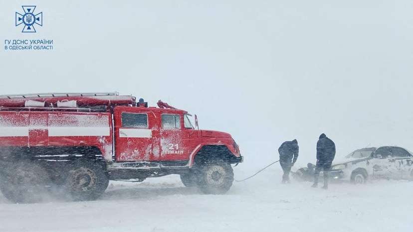 Emergency workers release a car which is stuck in snow during a heavy snow storm in Odesa region