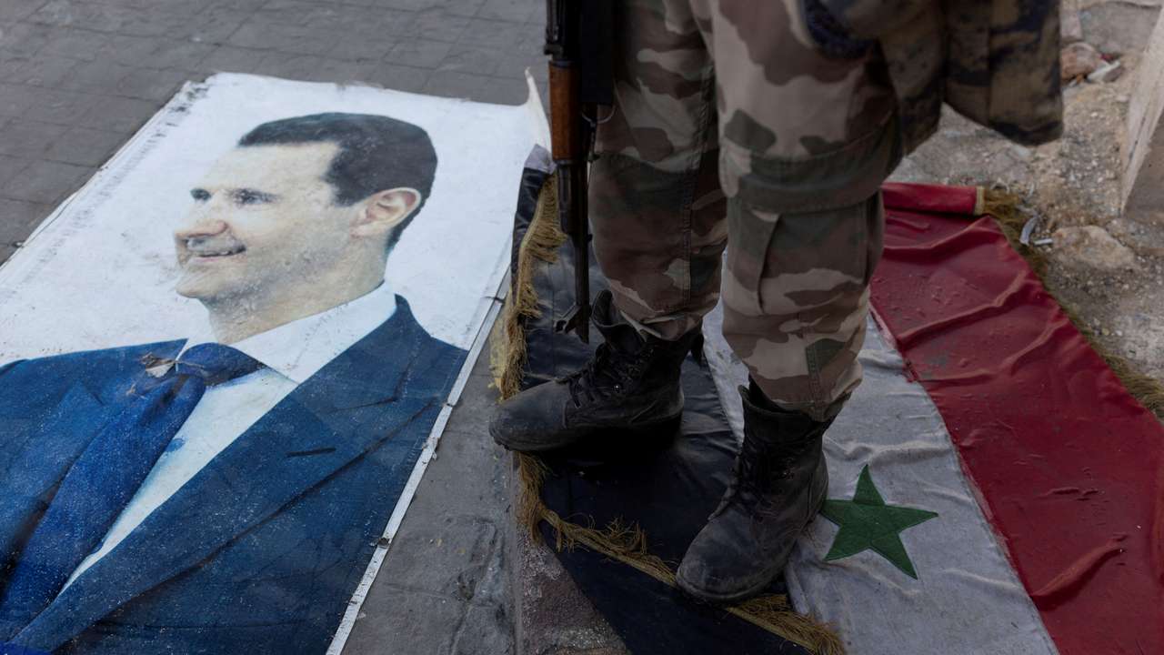 FILE PHOTO: Fighters of the ruling Syrian body steps on a Syrian flag under Bashar al-Assad rule in Aleppo