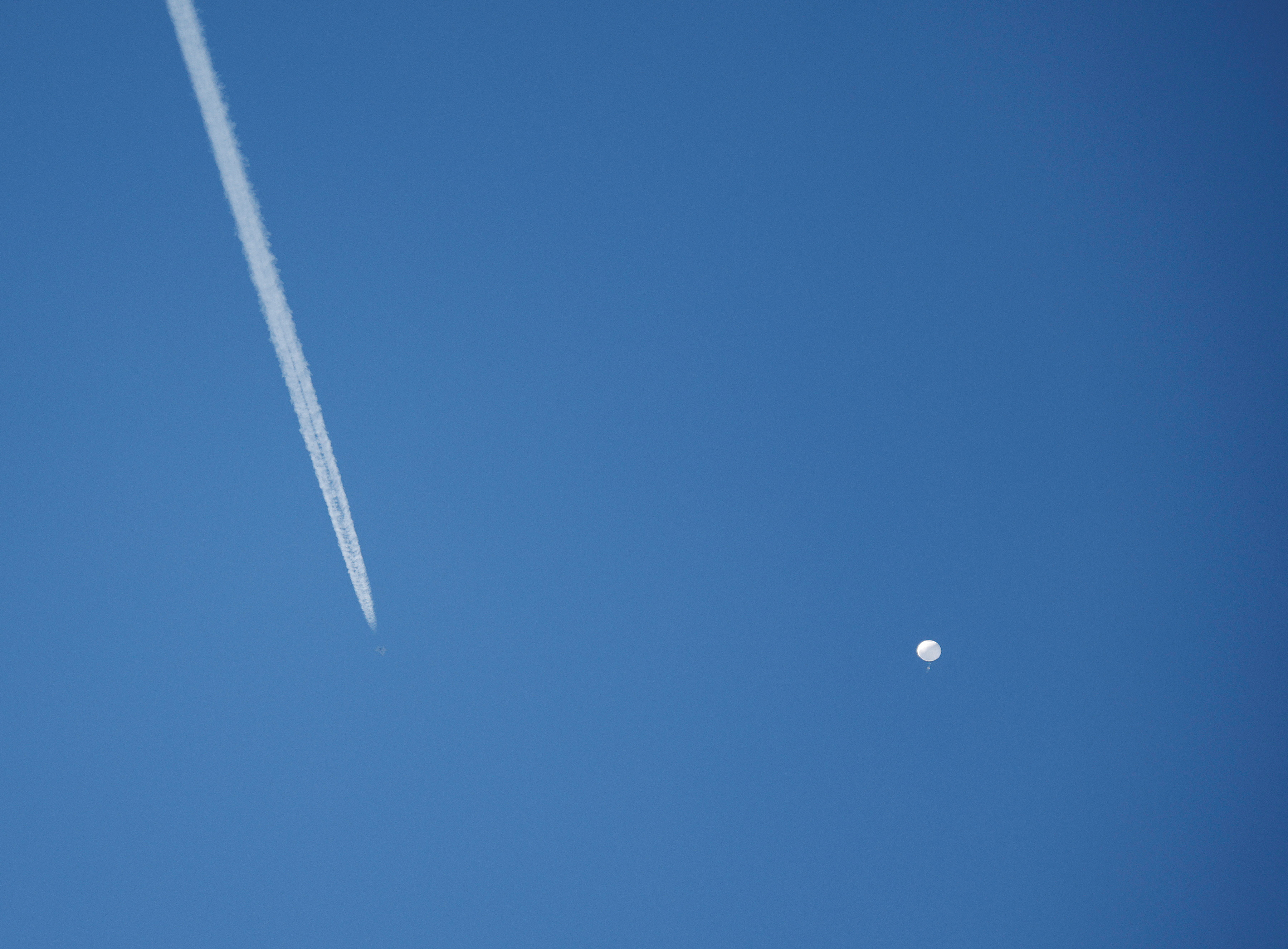 A jet flies by a suspected Chinese spy balloon as it floats off the coast in Surfside Beach