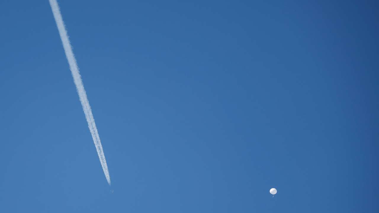 A jet flies by a suspected Chinese spy balloon as it floats off the coast in Surfside Beach