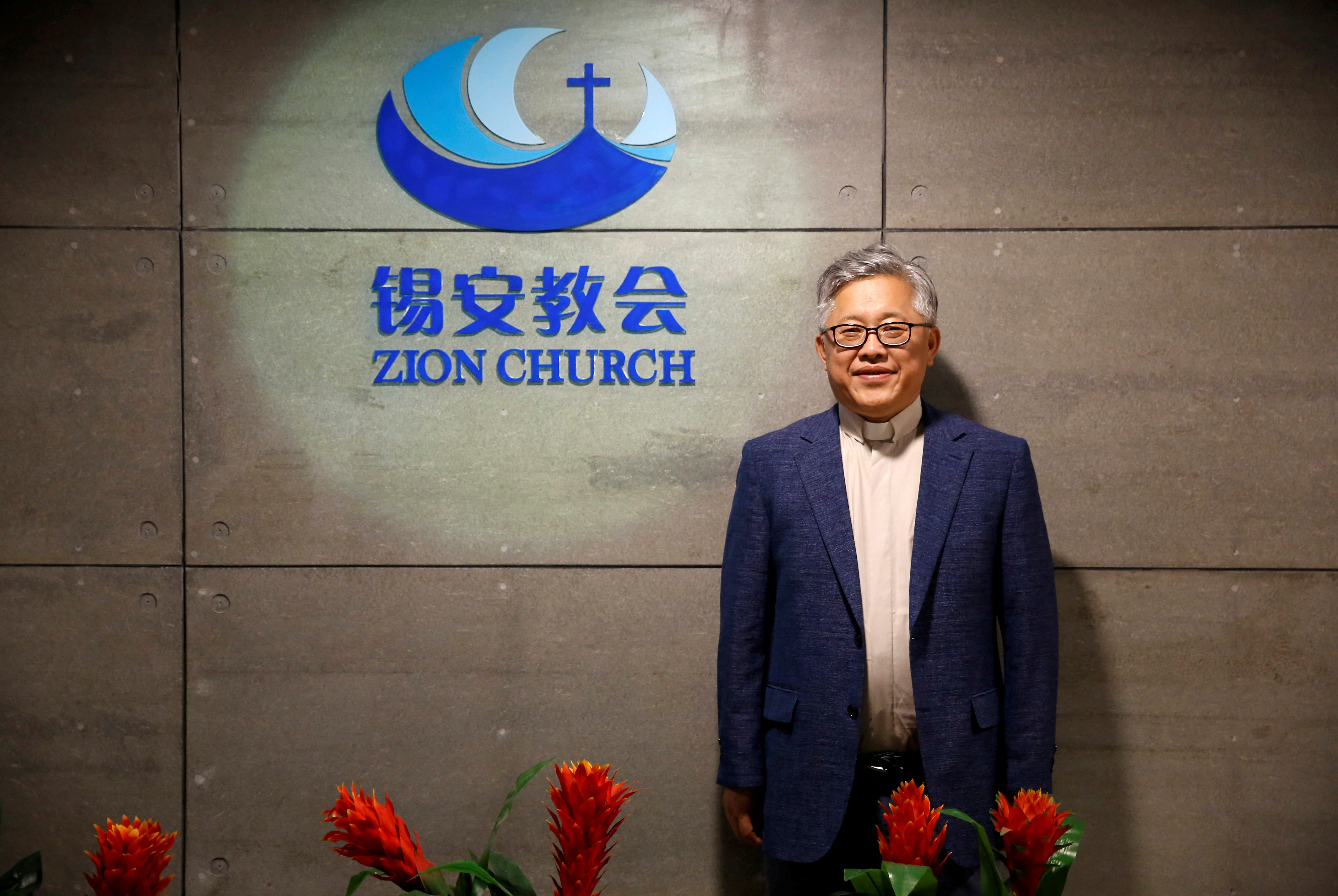 FILE PHOTO: The head pastor of the Zion church in Beijing Jin Mingri poses for picures in the lobby of the unofficial Protestant "house" church in Beijing