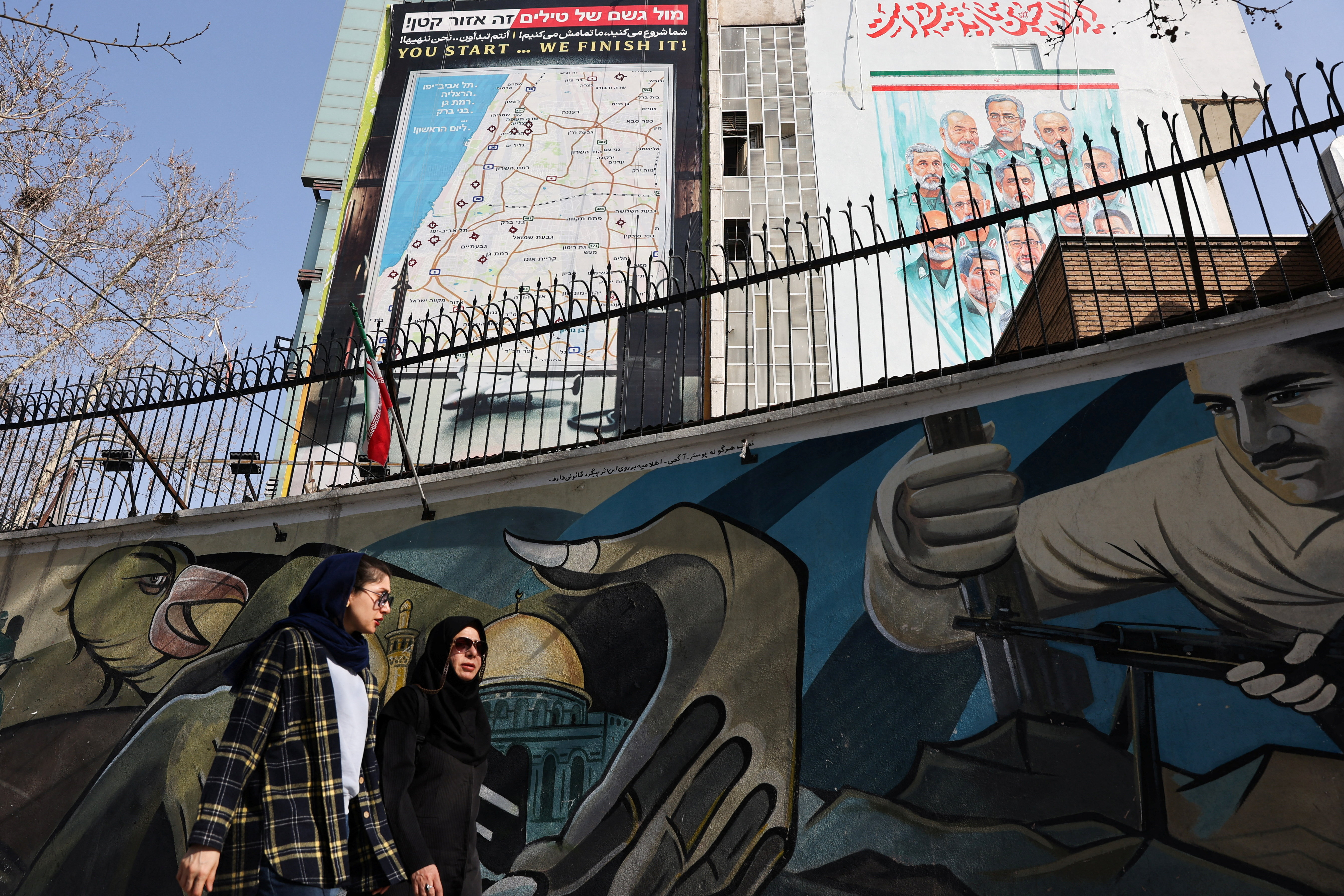 Iranian women walk past an anti-Israeli billboard in Tehran