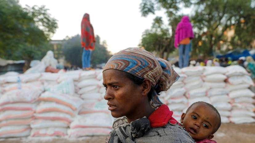 FILE PHOTO: Woman carries an infant as she queues in line for food, at the Tsehaye primary school, in Shire