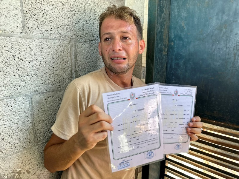 Palestinian father mourns twins killed in an Israeli strike while bringing their birth certificates