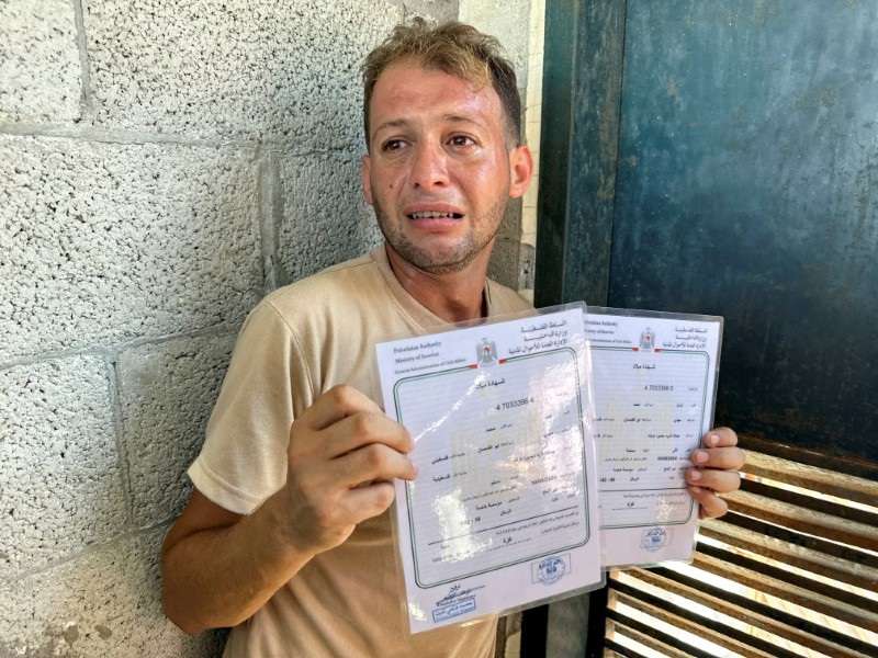 Palestinian father mourns twins killed in an Israeli strike while bringing their birth certificates