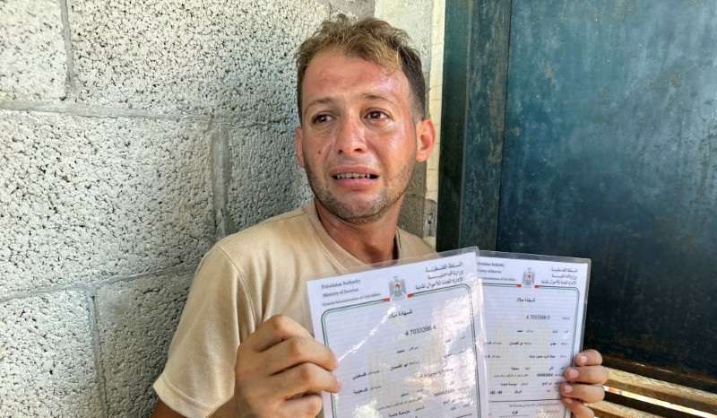 Palestinian father mourns twins killed in an Israeli strike while bringing their birth certificates