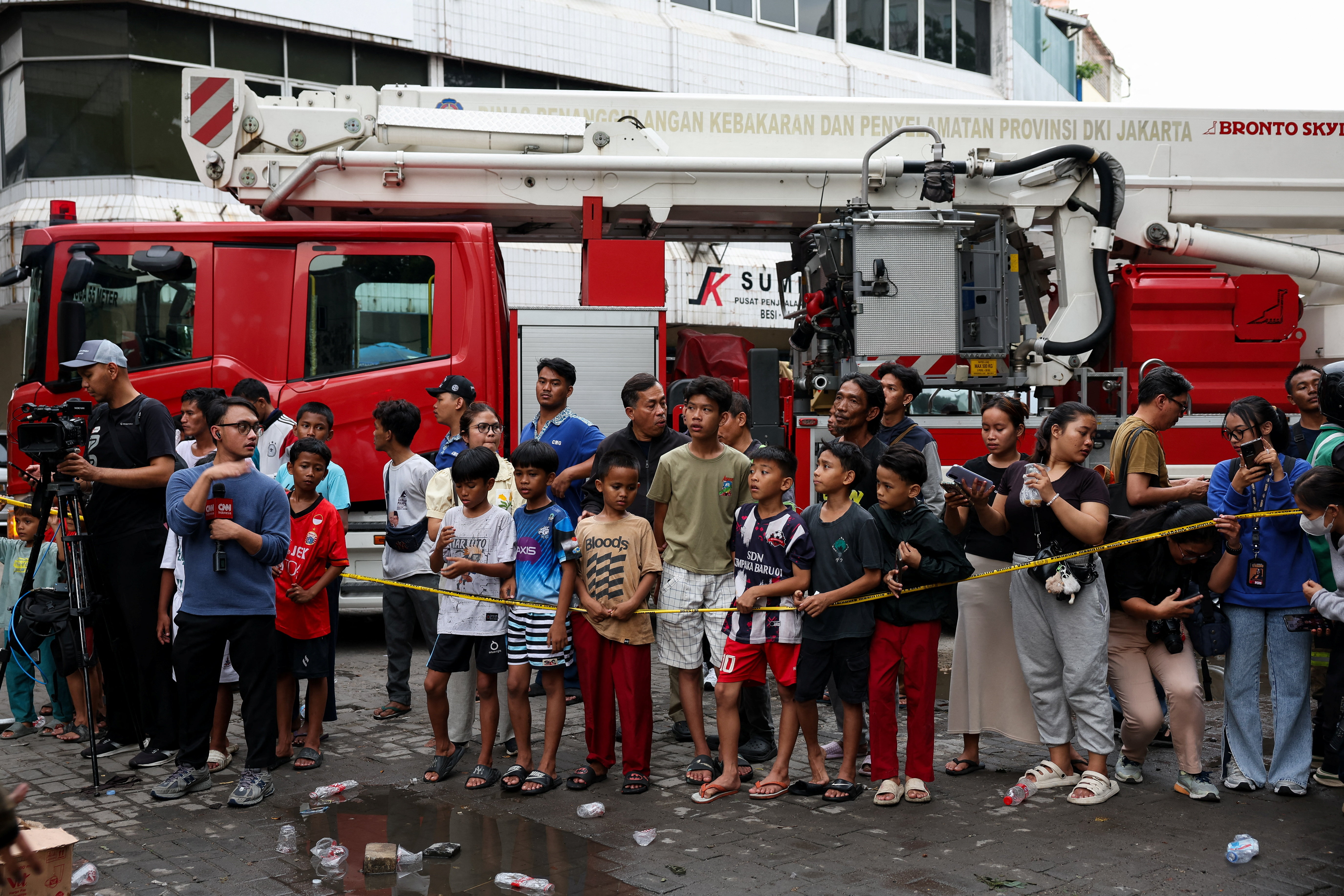 People watch a seven-storey building damaged by fire in Jakarta