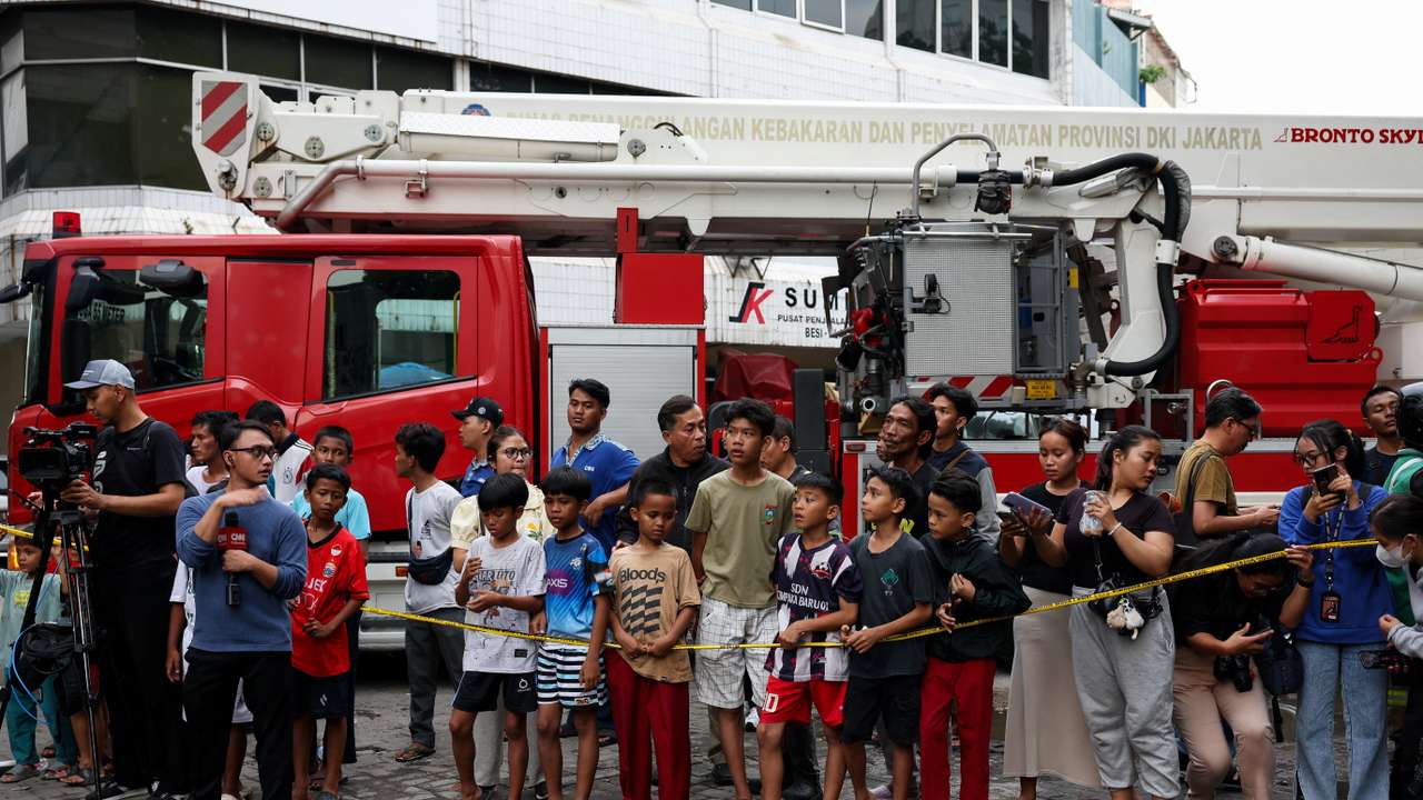 People watch a seven-storey building damaged by fire in Jakarta