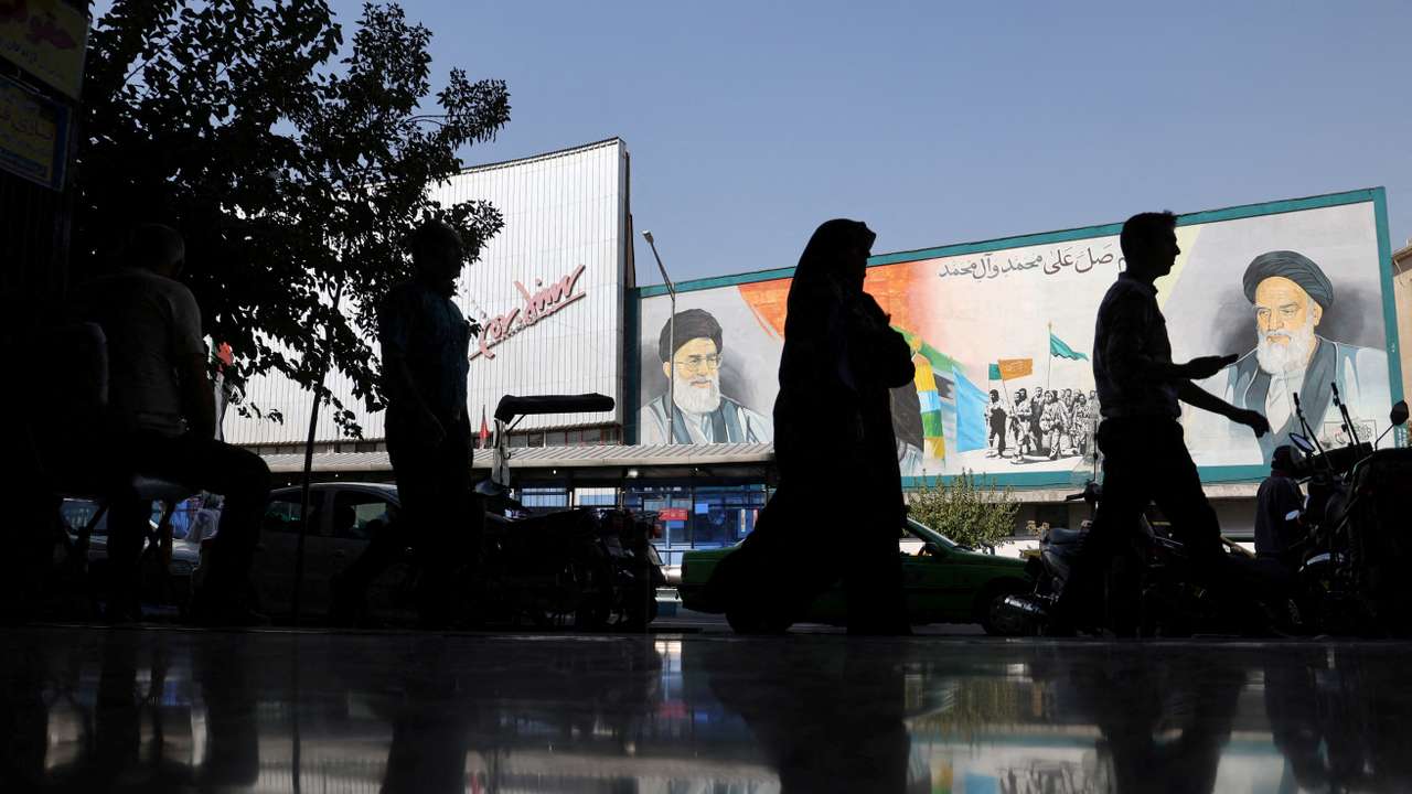 FILE PHOTO: People walk past a mural depicting the late leader of the Islamic Revolution Ayatollah Ruhollah Khomeini and Iran's Supreme Leader Ayatollah Ali Khamenei on a building in a street in Tehran