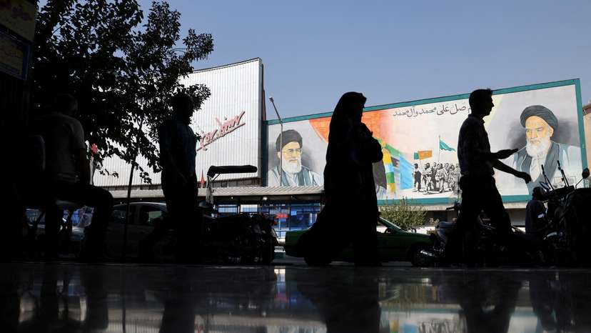 FILE PHOTO: People walk past a mural depicting the late leader of the Islamic Revolution Ayatollah Ruhollah Khomeini and Iran's Supreme Leader Ayatollah Ali Khamenei on a building in a street in Tehran