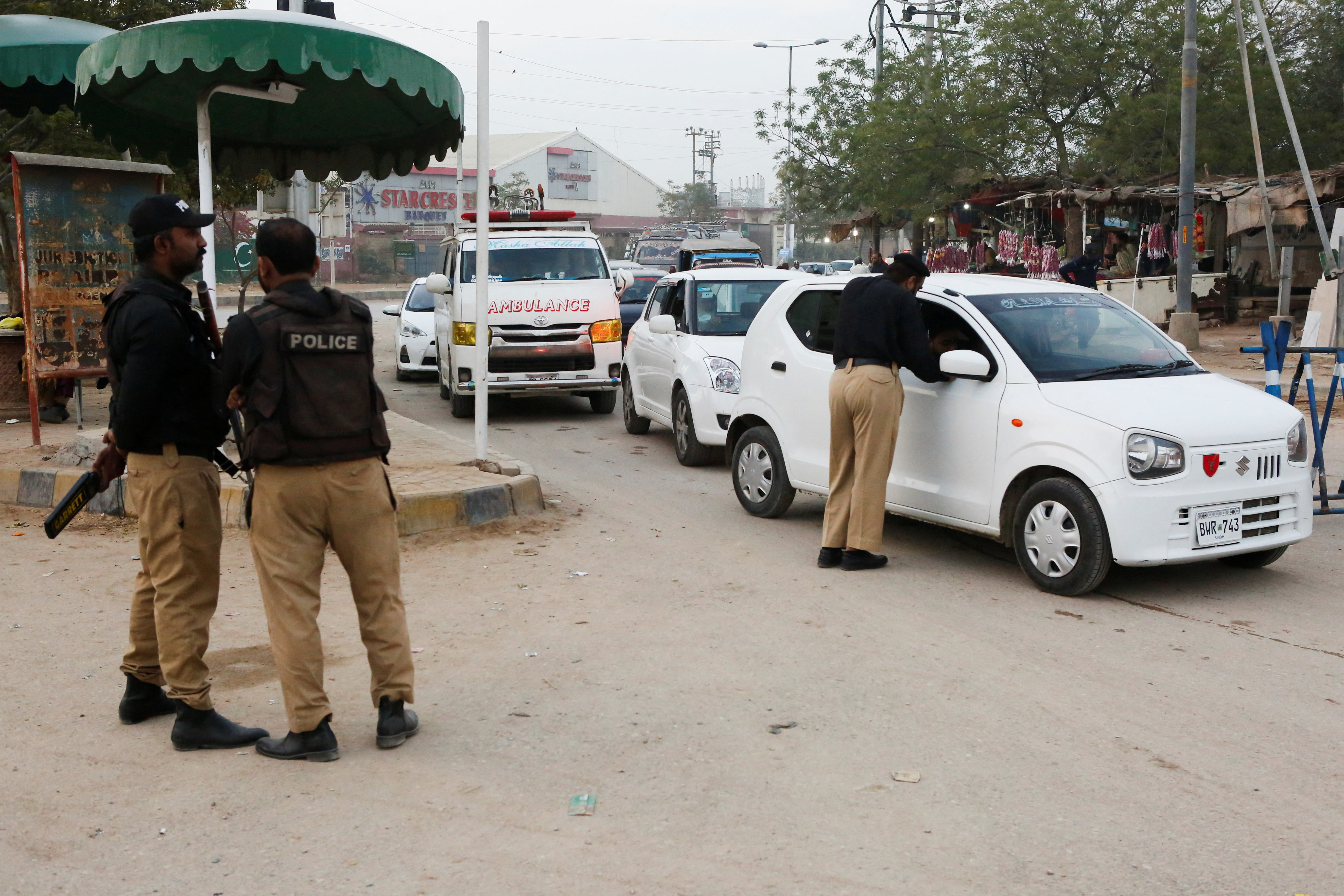 Police officers check vehicles as a security measure, following exchanges of fire between Pakistani and Afghan forces, along a road leading to the airport in Karachi
