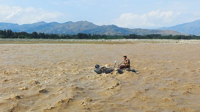 A rescue worker rows a raft while searching for survivors, after tourists, who were on a picnic, were swept away by overflowing floodwaters in the Swat River