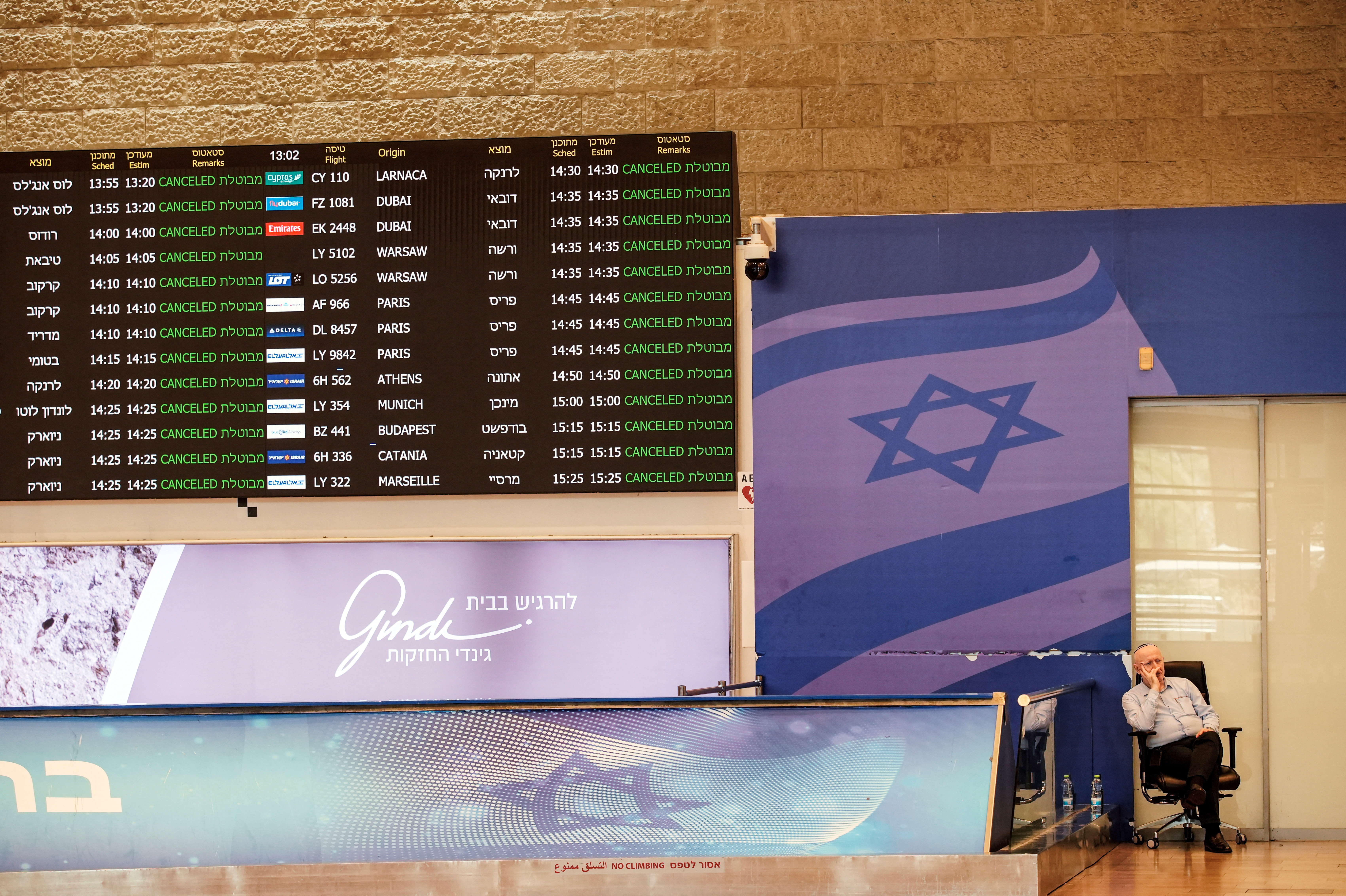 A staff of Ben Gurion International Airport, sits at the arrivals terminal as all flights from and to the airport are indicated cancel, following Israel's attack in Iran last night in Lod near Tel Aviv
