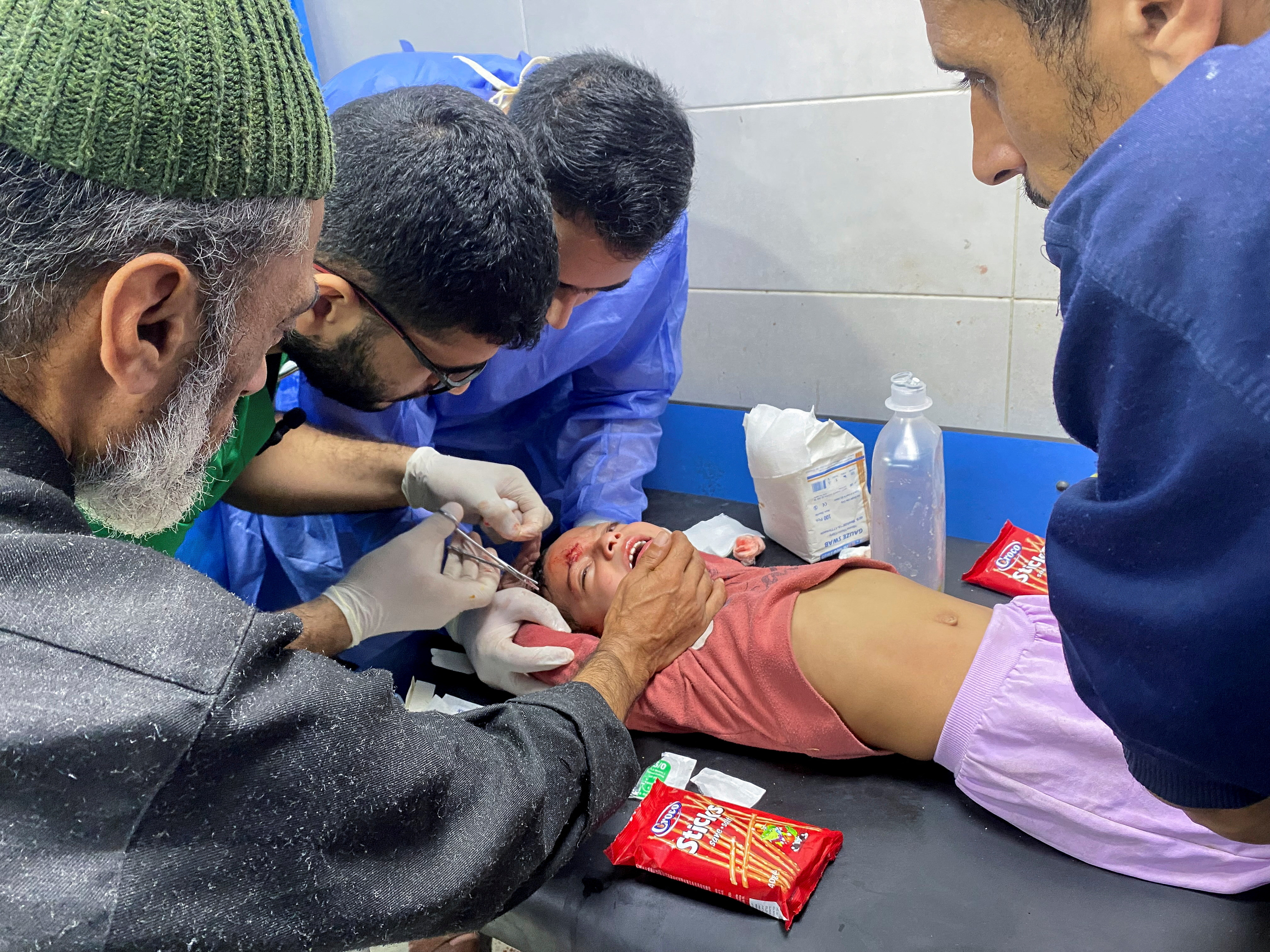FILE PHOTO: Palestinian girl Orheen Al-Dayah, who was injured on her forehead in an Israeli strike, has her wounds stitched without anaesthesia, at Al Shifa hospital in Gaza City