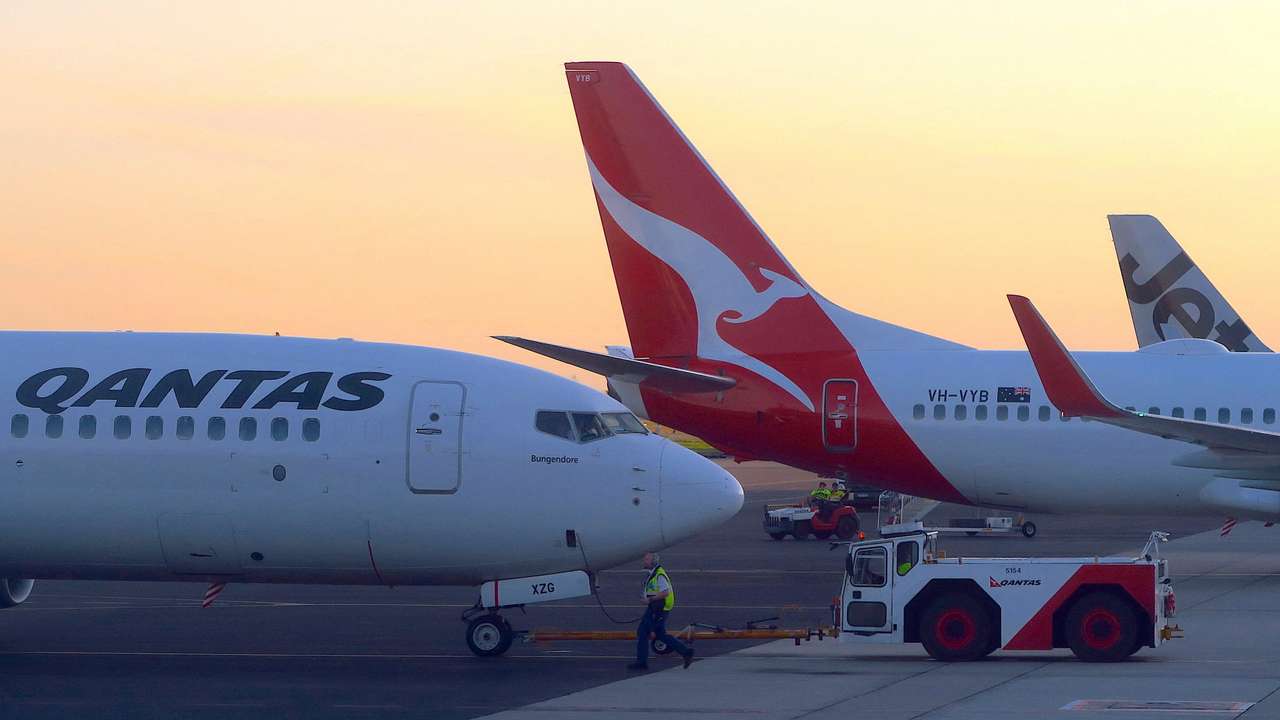 FILE PHOTO: Workers are seen near Qantas Airways, Australia's national carrier, Boeing 737-800 aircraft on the tarmac at Adelaide Airport