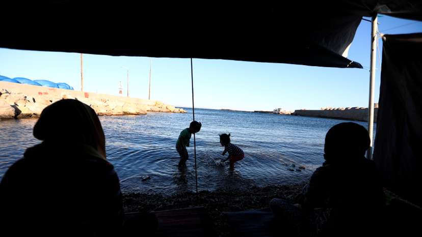 Ruba and Faten from Syria sit watching children play at the beach outside the Souda refugee camp in Chios Island, Greece