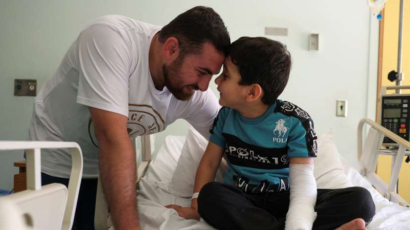 5-year-old Adam Afana, the first Palestinian child wounded in Israel's war on Gaza to land in Lebanon, plays with his uncle Eid Afana, as he sits on a hospital bed in Beirut