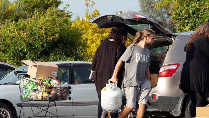 People take out products from their supermarket shopping cart and load them into their car outside Pak'nSave supermarket