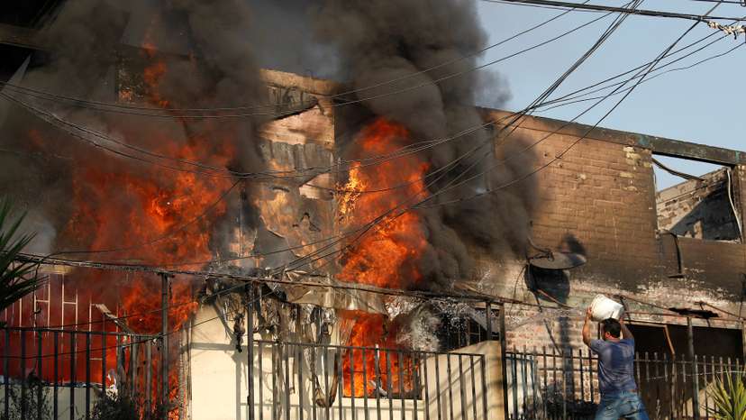 A man tries to extinguish a fire burning a house during the spread of wildfires in Vina del Mar