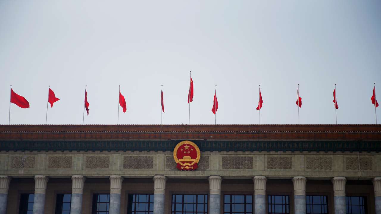 Flags flutter above the Chinese national emblem at the Great Hall of the People in Beijing