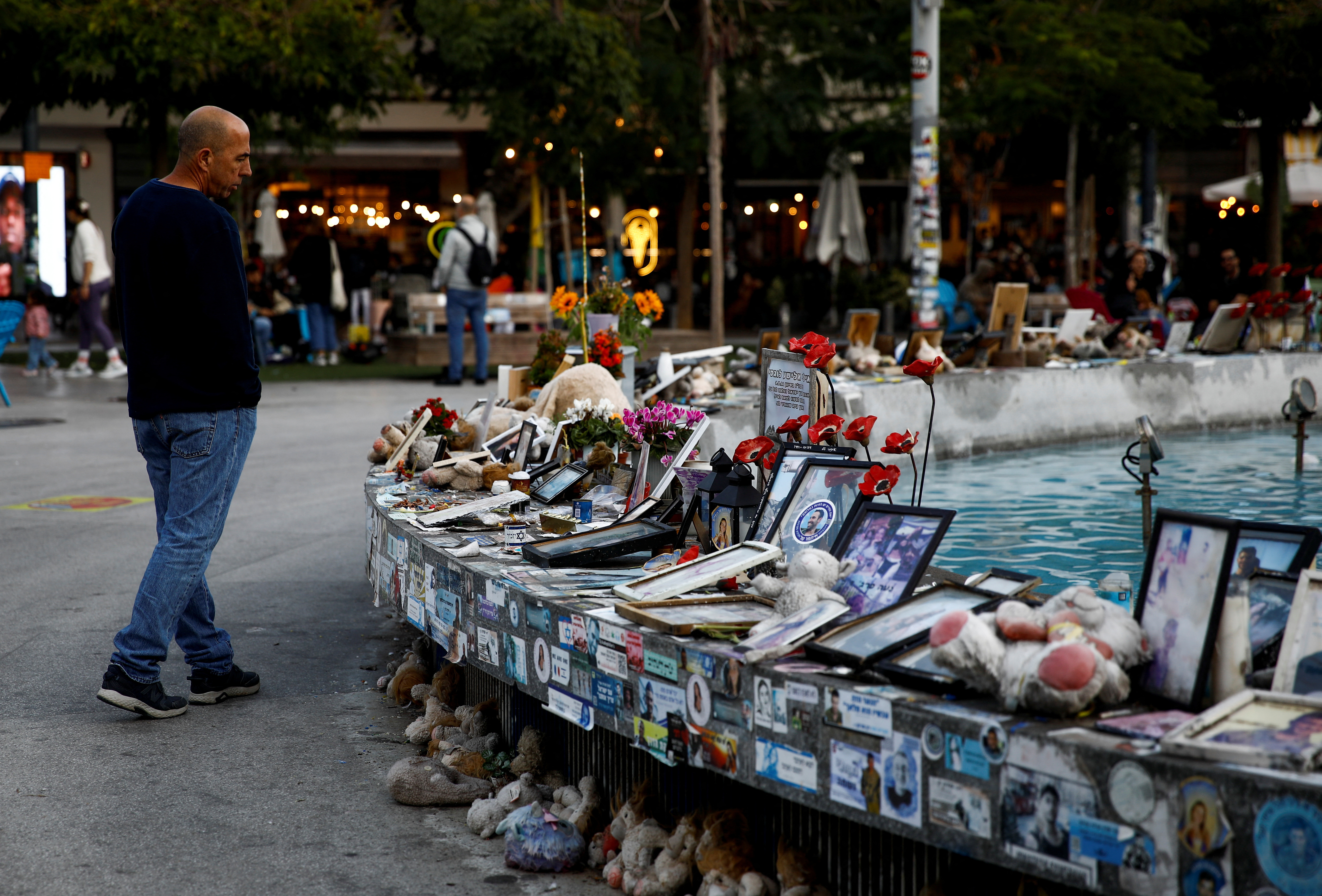 Man looks at pictures and memorabilia related to fallen soldiers, hostages and people killed during the October 7, 2023 attack, in Tel Aviv
