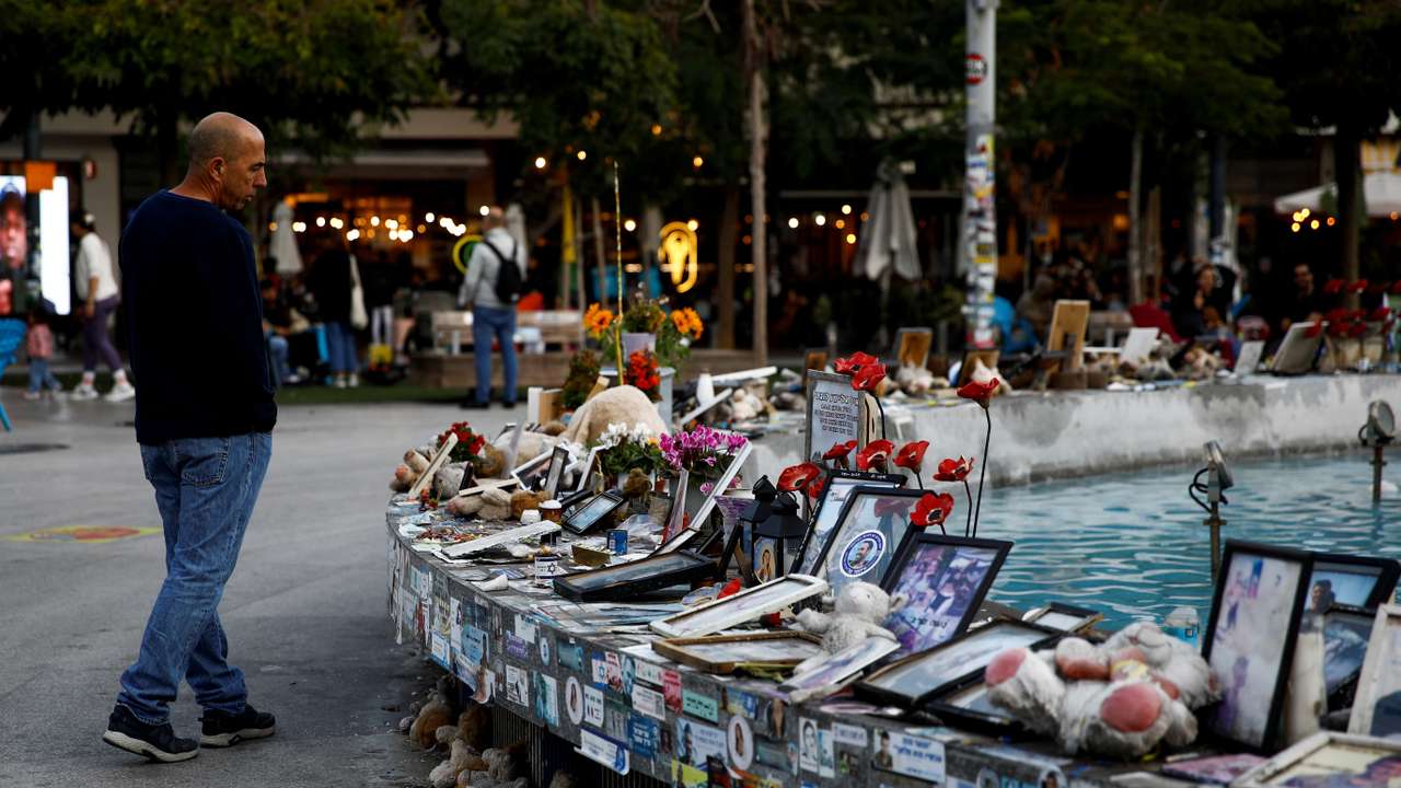 Man looks at pictures and memorabilia related to fallen soldiers, hostages and people killed during the October 7, 2023 attack, in Tel Aviv
