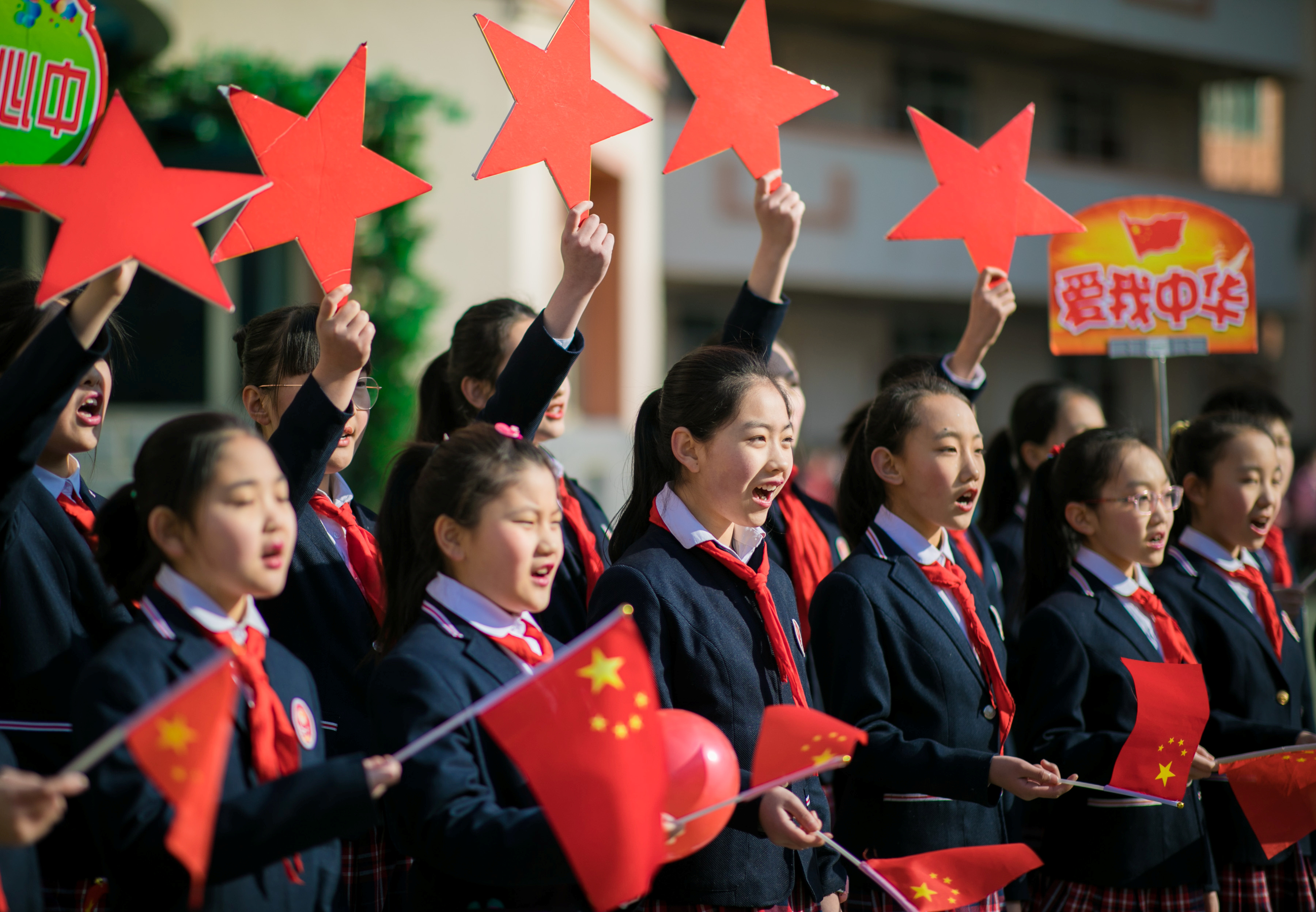 Students hold Chinese flags and cutouts of red stars as they perform a song titled "Me and my country", at a ceremony marking the primary school's new semester in Hohhot