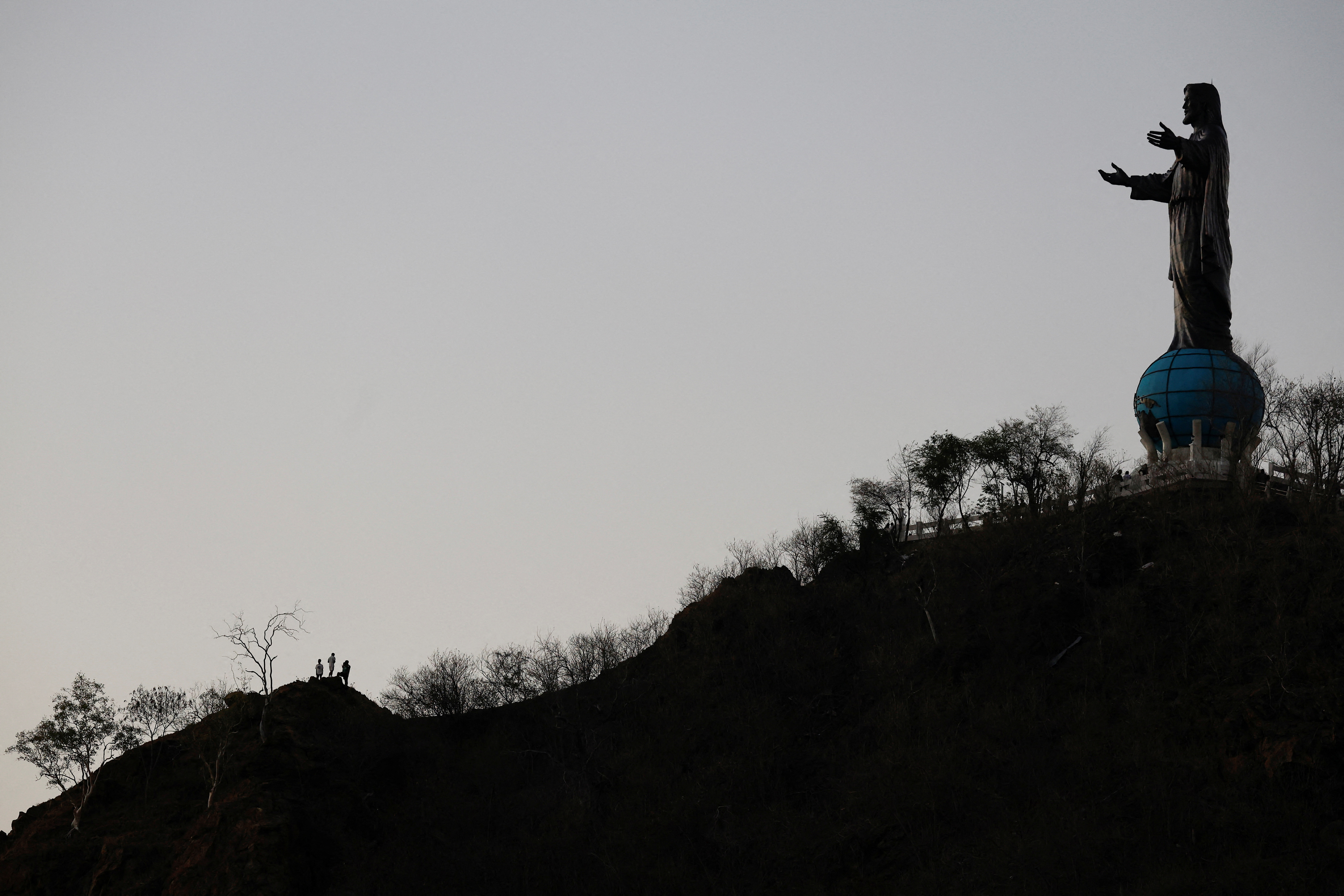 People stand on the hill near Cristo Rei, a statue depicting Jesus Christ, in Dili