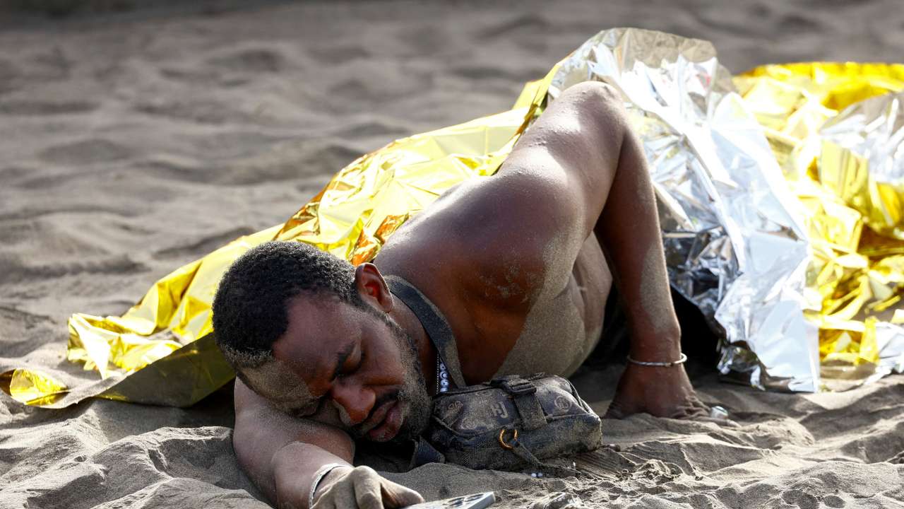 A migrant rests on the sand after arriving in a fiber boat at Las Burras beach in San Agustin