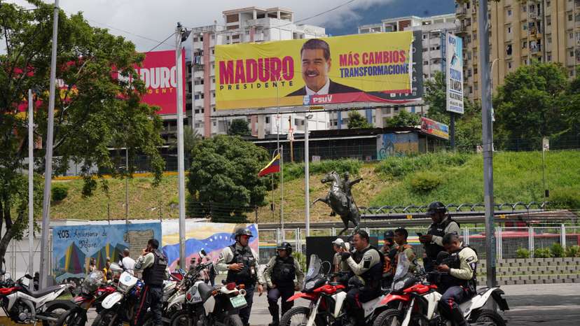 Police officers stand near image of Venezuela's President Maduro, in Caracas