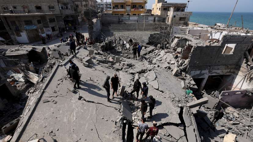 Palestinians inspect the site of an Israeli strike on a residential building, in Deir Al-Balah