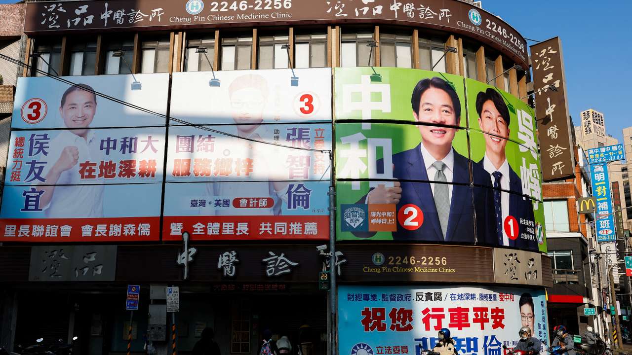 People ride past campaign ads in Taipei