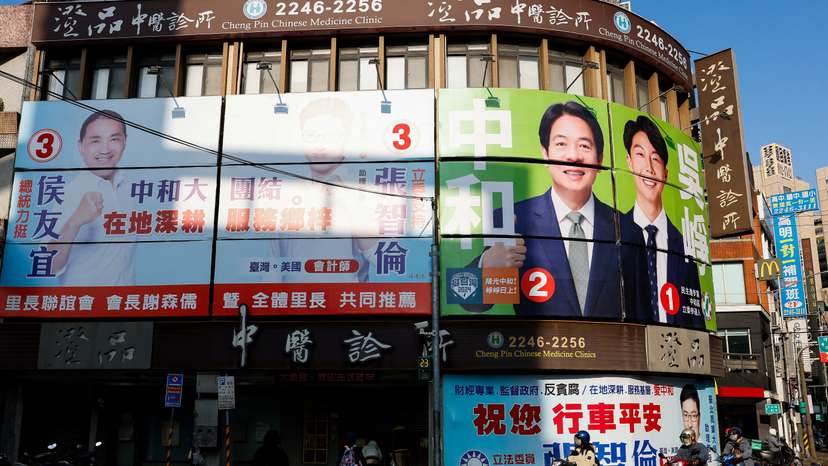 People ride past campaign ads in Taipei