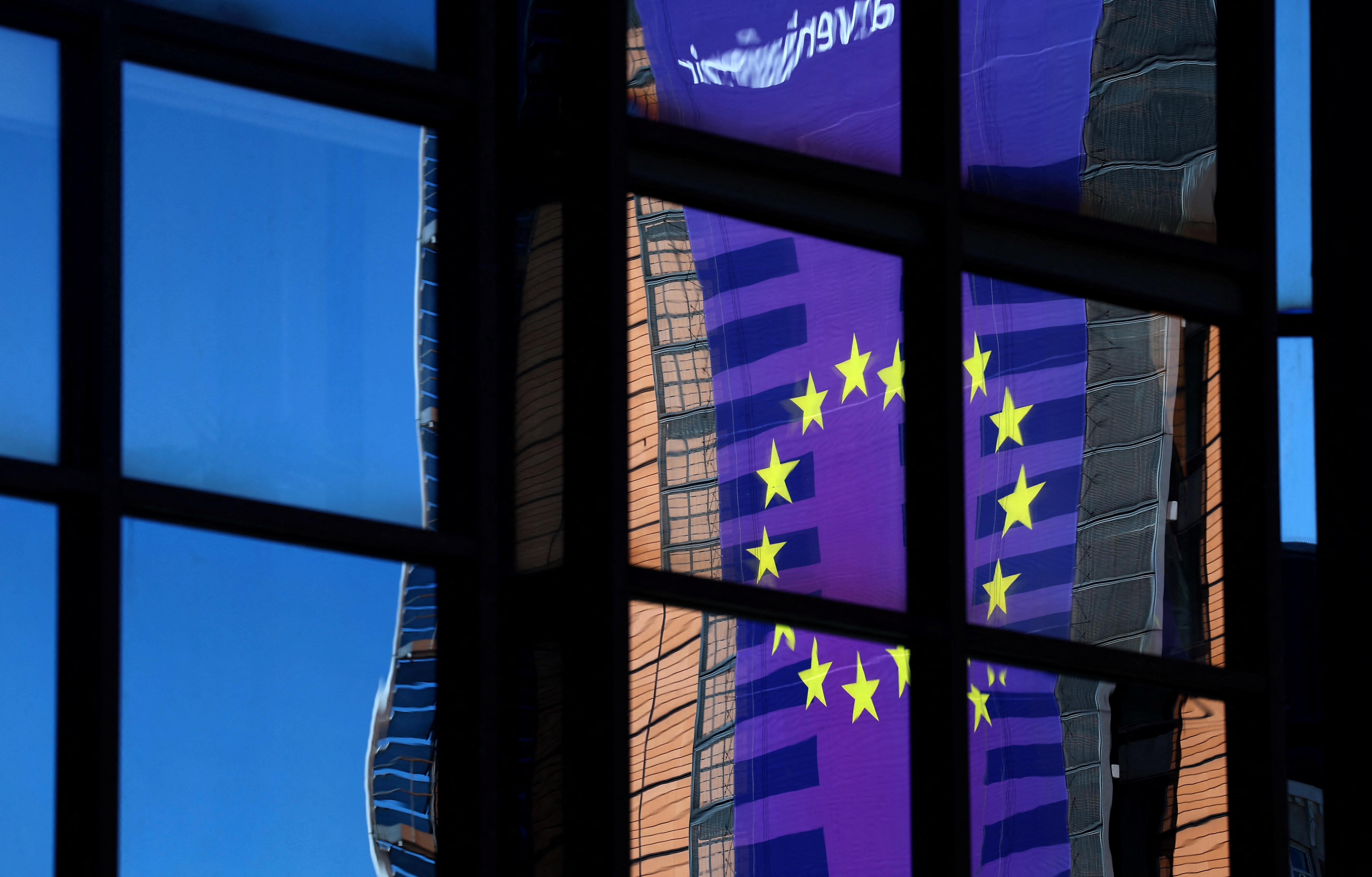 A banner depicting an European Union flag is reflected  in a window outside the EU Council headquarters in Brussels