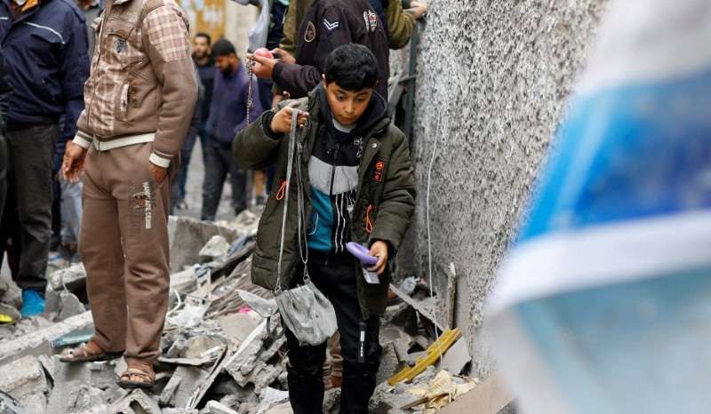 Palestinians walk at the site of an Israeli strike, in Rafah