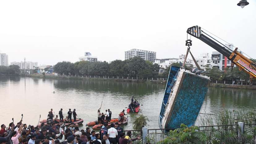 A crane pulls out a boat which capsized carrying children and teachers who were on a picnic in Harni Lake in Vadodara