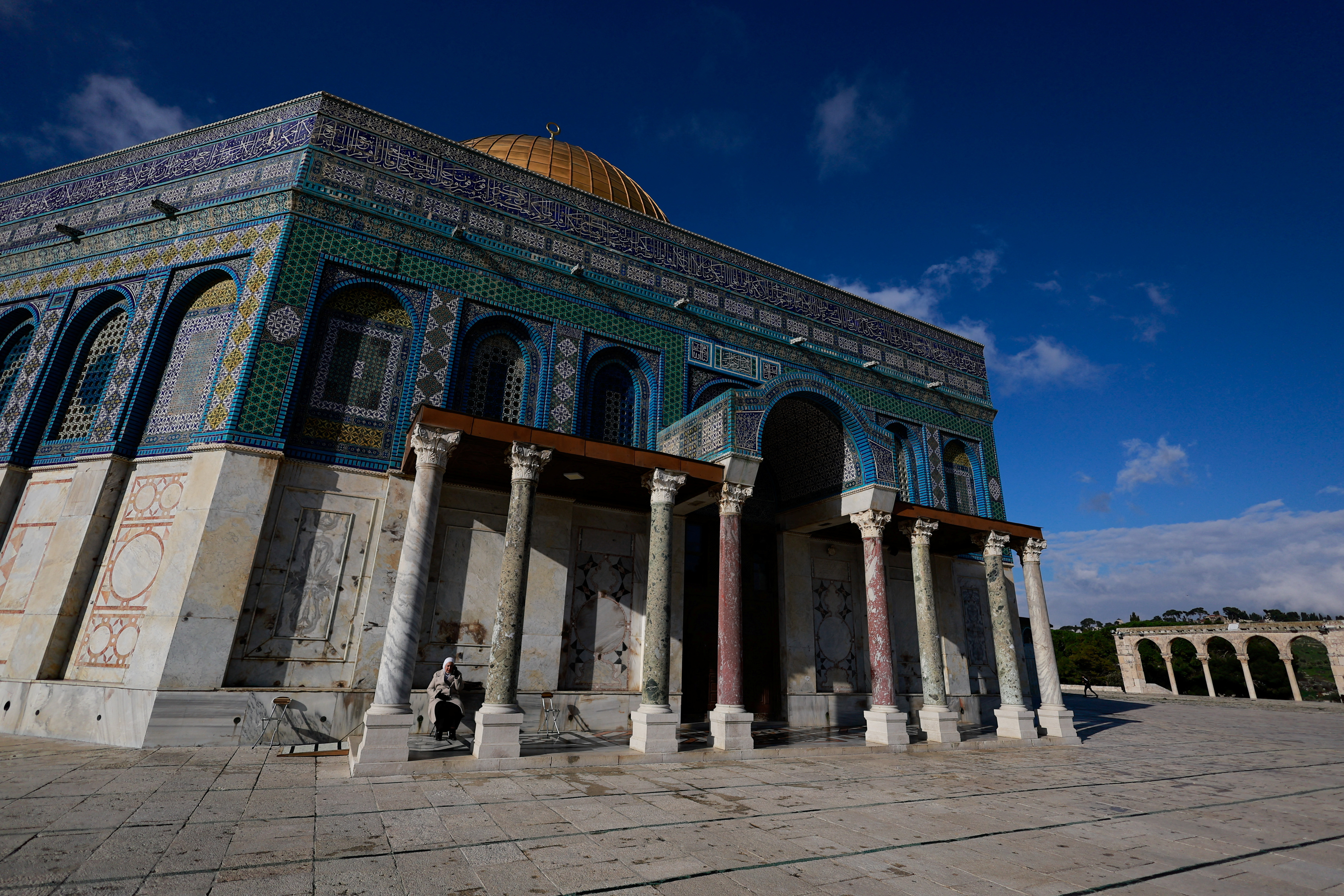 A Palestinian woman rests in front of the Dome of the Rock on Al-Aqsa compound, also known to Jews as the Temple Mount, in Jerusalem's Old City