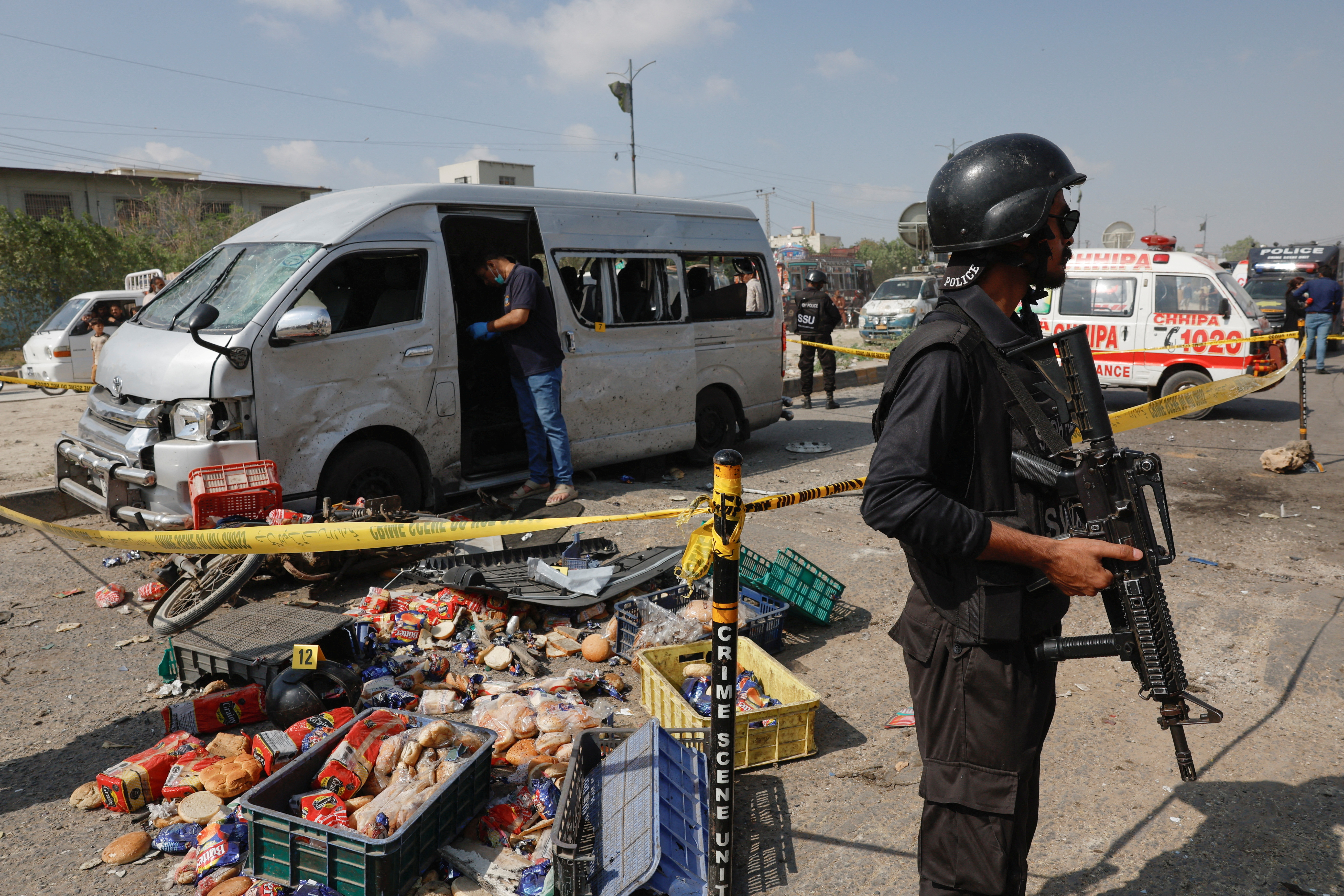 Police officer stands guard near a cordoned damaged vehicle after a suicide blast in Karachi