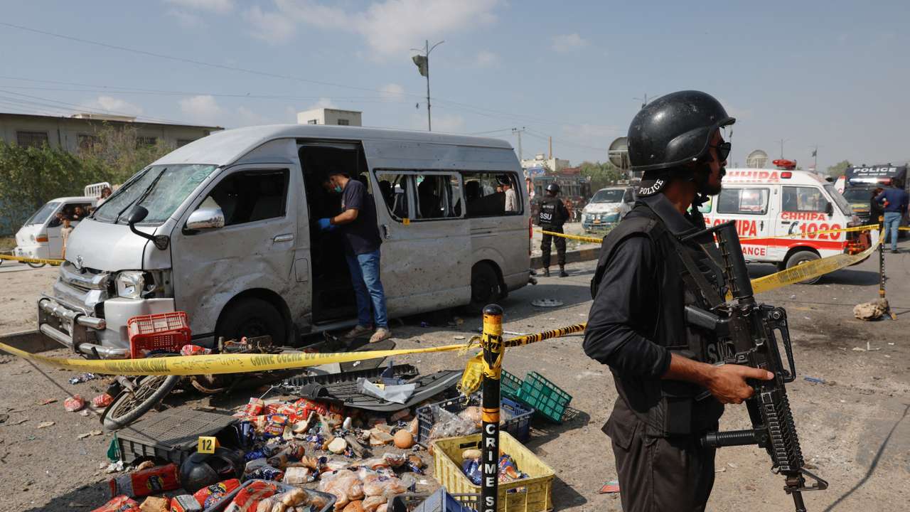 Police officer stands guard near a cordoned damaged vehicle after a suicide blast in Karachi