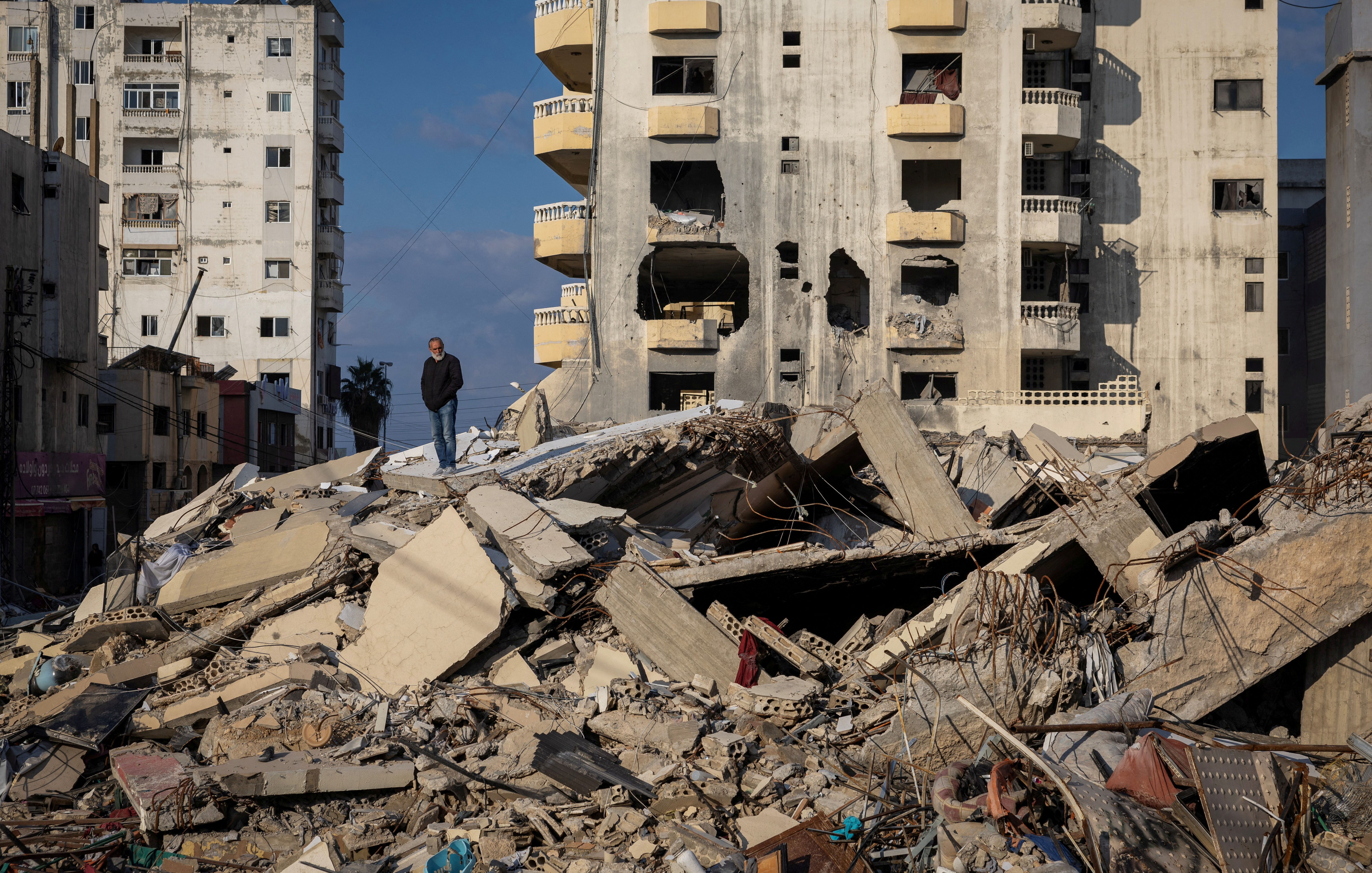 A man stands on the ruins of his house destroyed in an Israeli strike, after the ceasefire between Israel and Hezbollah, in Tyre
