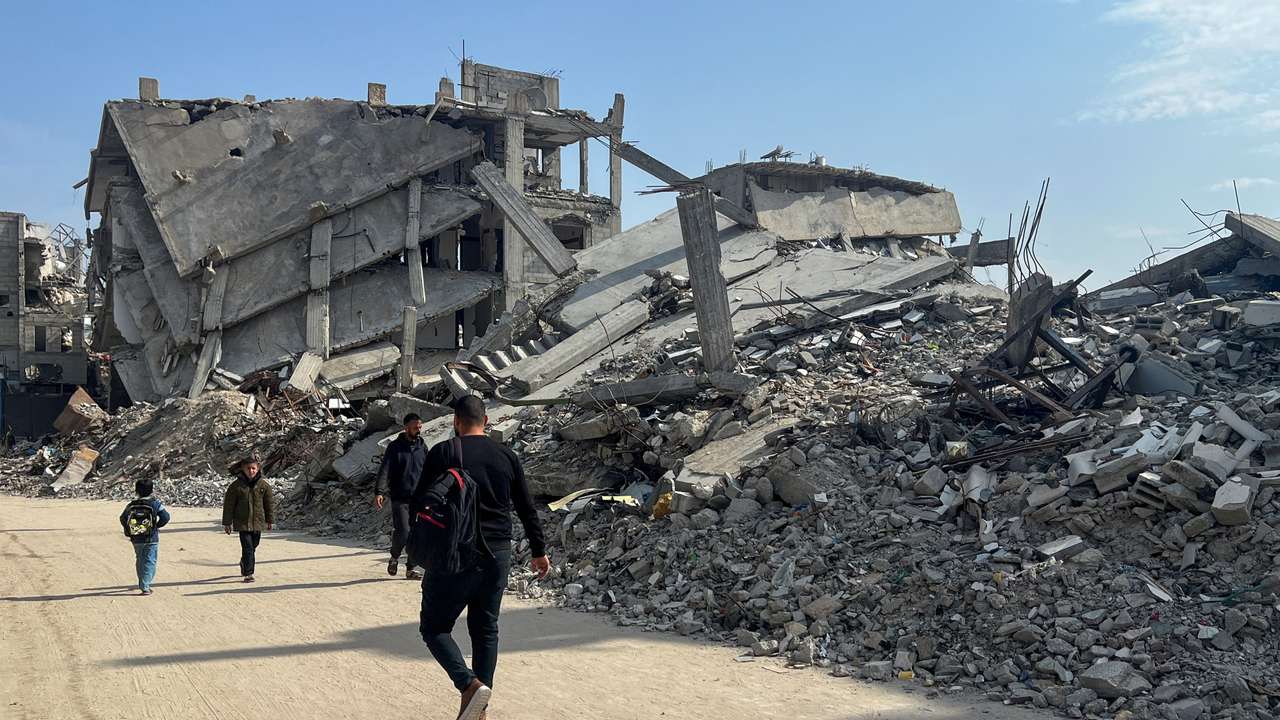 Palestinians walk past the rubble of destroyed houses, amid a ceasefire between Israel and Hamas, in Khan Younis in the southern Gaza Strip