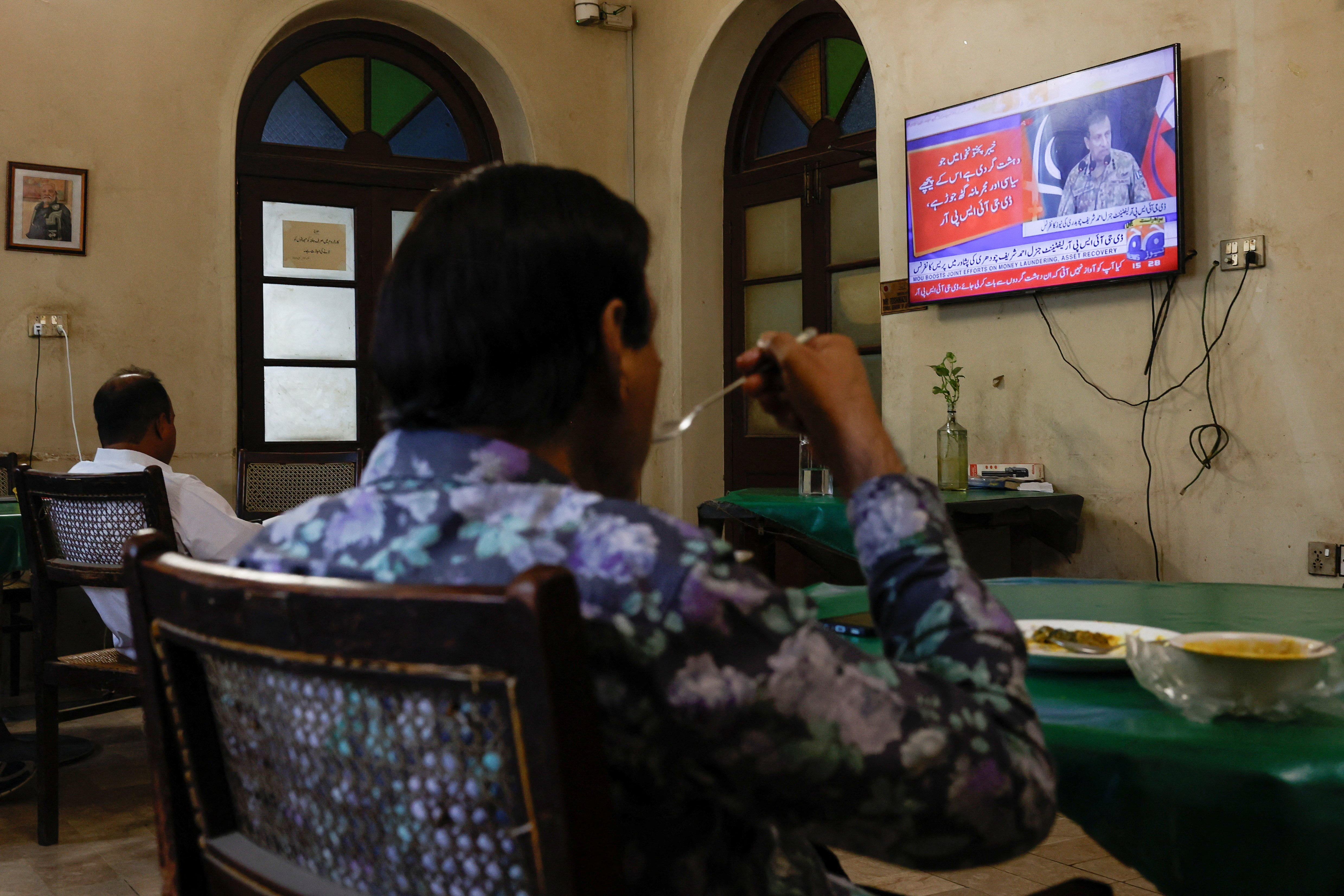 People watch a televised press briefing by Ahmed Sharif Chaudhry, Director General of the Inter-Services Public Relations wing of the Pakistan Armed Forces, in Karachi