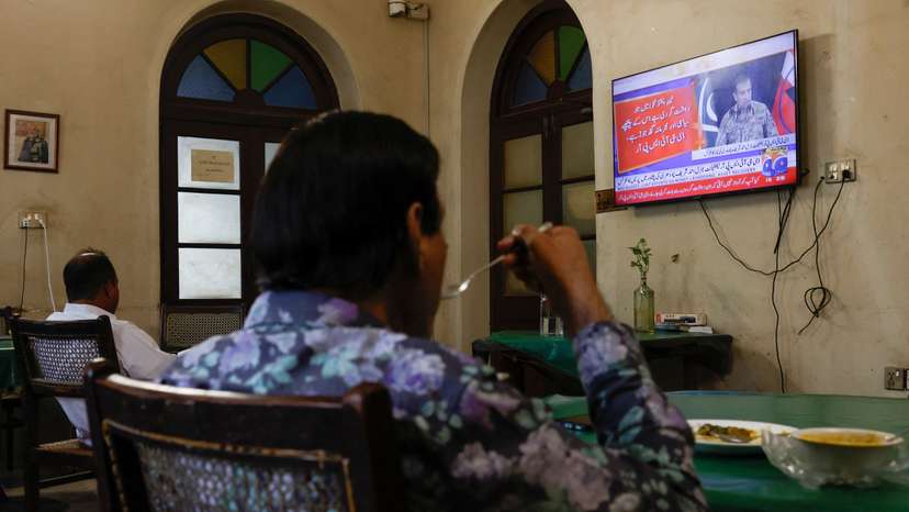 People watch a televised press briefing by Ahmed Sharif Chaudhry, Director General of the Inter-Services Public Relations wing of the Pakistan Armed Forces, in Karachi