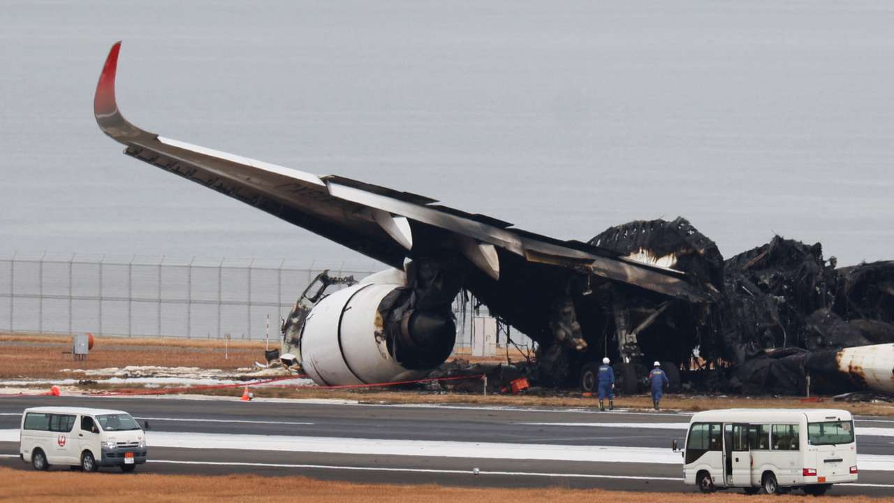 Officials investigate a burnt Japan Airlines (JAL) Airbus A350 plane after a collision with a Japan Coast Guard aircraft at Haneda International Airport in Tokyo