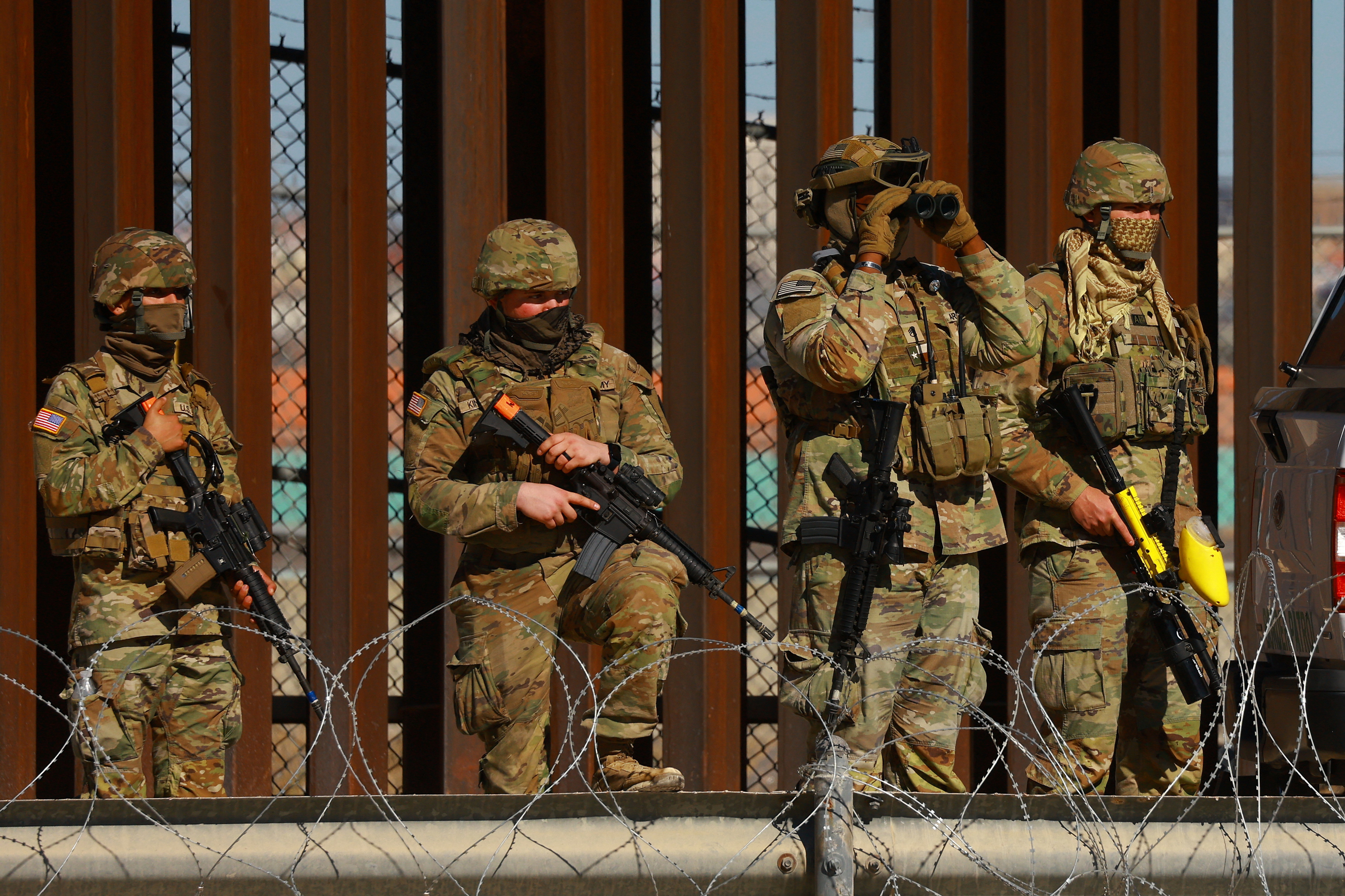 Members of the Texas National Guard stand guard near the border wall between Mexico and the United States