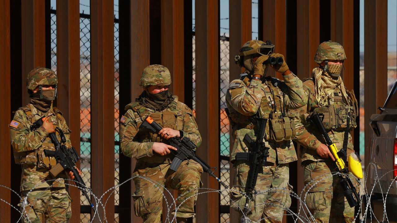 Members of the Texas National Guard stand guard near the border wall between Mexico and the United States