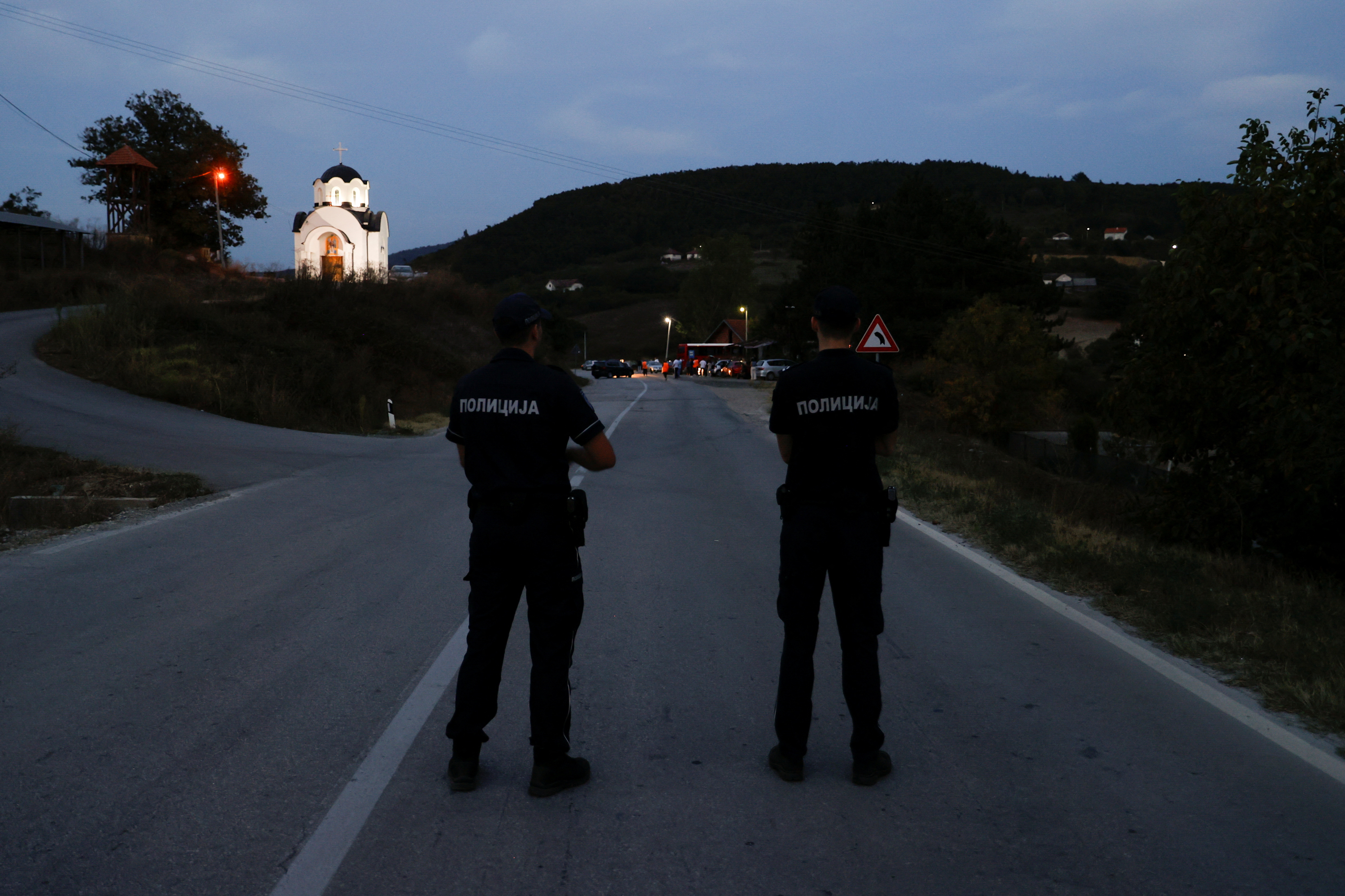 Police officers stand guard as protestors partially block the road near the main Kosovo-Serbia border crossing in Merdare